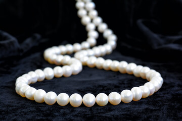 Natural pale pearl necklace on a black velvet background, closeup