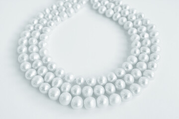 Three rows of natural pearl necklace on white background, blue tinted