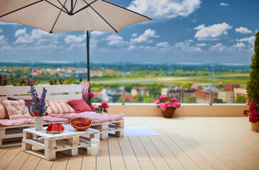 cute, cozy pallet furniture with colorful pillows at summer rooftop patio, lounge outdoor space