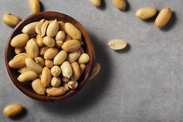 Peanuts in wooden bamboo bowl on concrete background. Nuts.
