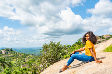 young african woman sitting on a rock, resting on a hike