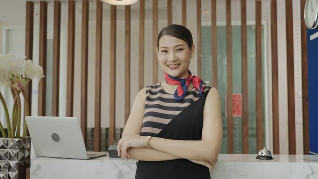 The hotel receptionist is standing in front of the hotel lobby with a smile of congratulations.
