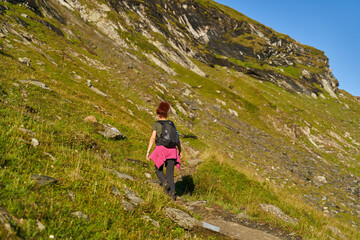Fototapeta premium Woman hiker with backpack on a trail in the mountains