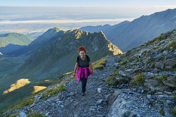 Naklejka premium Woman hiker with backpack on a trail in the mountains