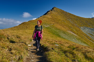 Fototapeta premium Woman hiker with backpack on a trail in the mountains