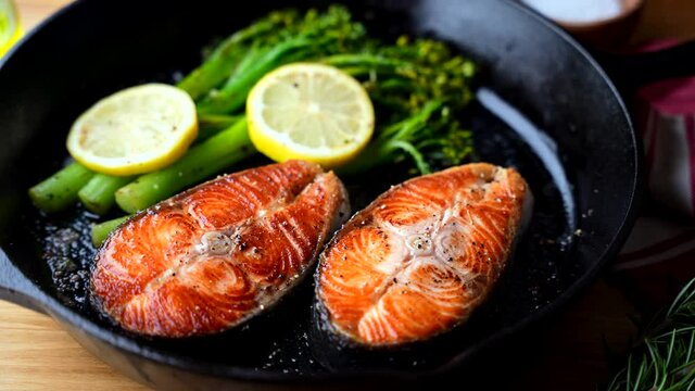 roasted salmon fillet steak with broccolini and lemon slice on iron skillet pan