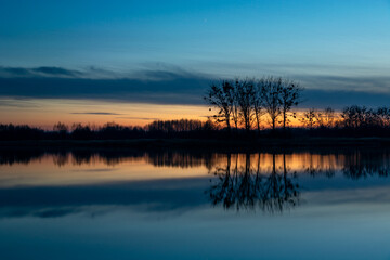 Reflection of trees in the water after sunset