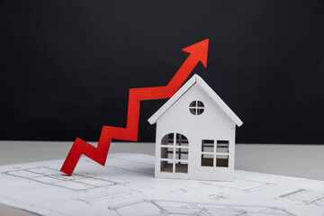 Building cost and investment concept. White house and arrow up on it with a drawing
