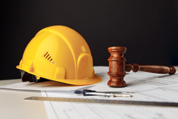Gavel with yellow helmet. Construction law concept - obrazy, fototapety, plakaty