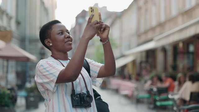 Black female tourist taking photos on smartphone