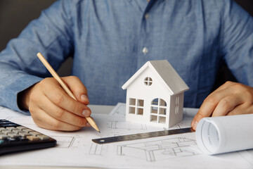 Construction engineer working on blueprint architectural project at desk in office using pencil