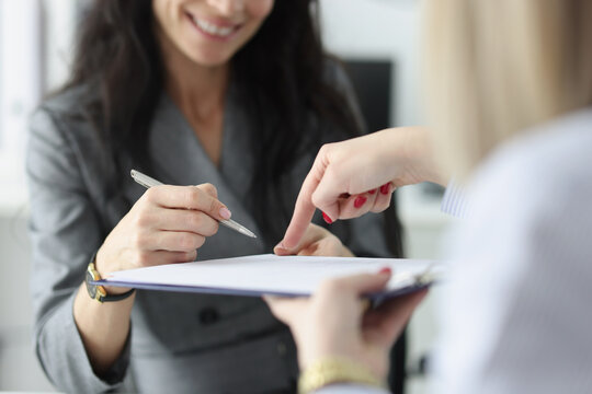 Lawyer pointing to insurance contract showing client to woman where to sign