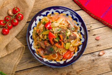 Lagman asian soup with noodles and meat top view on old wooden table