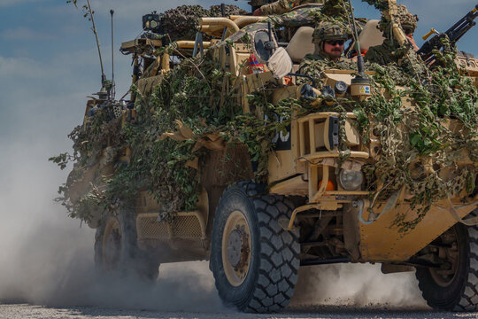 British army Supacat Jackal 4x4 rapid assault, fire support and reconnaissance vehicle throwing up clouds of dust at speed on exercise, Wilts UK