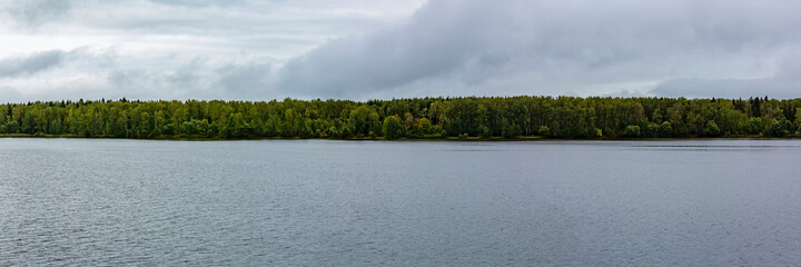 Scenic river landscape with green trees in early autumn
