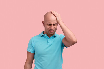 Facepalming. Upset bald homosexual man with bristle keeps hand on forehead, feels stressed, regrets...