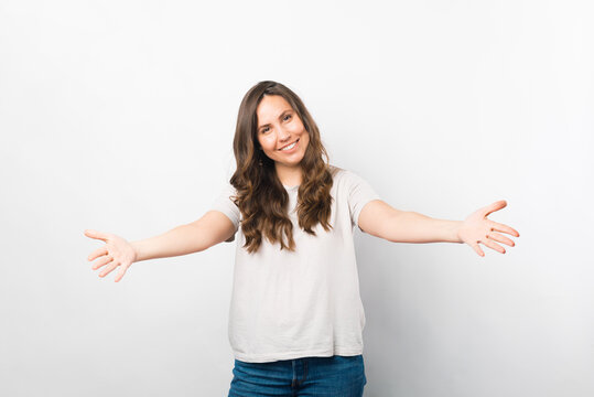 Come here I will give you a hug. Portrait of a woman with arms wide open over white background.