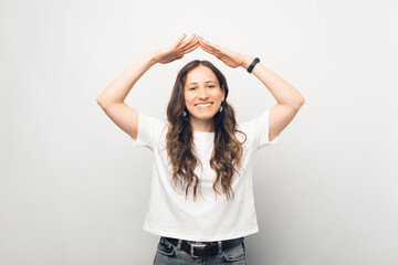 Cheerful smiling young woman is making the roof gesture over white background.