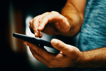 Fototapeta Primer plano de la mano de un hombre sosteniendo su smartphone. Enviando un sms y compartiendo contenidos en las redes sociales desde el interior de la vivienda obraz