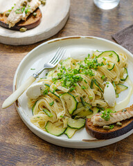 Spaghetti with zucchini and basil pesto on a white plate, rustic style