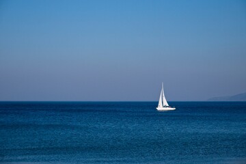 White sail boat on blue ocean.