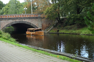Fototapeta na wymiar A boat under the bridge on the canal in the park of Riga. High quality photo