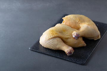 Raw chicken quarters, legs on board on gray background