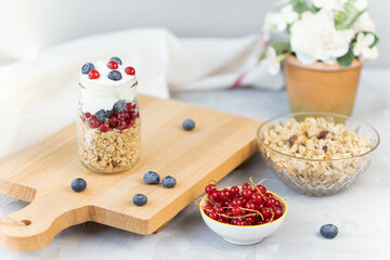 Toasted muesli or homemade granola with nuts and yogurt and berries in small glass jar