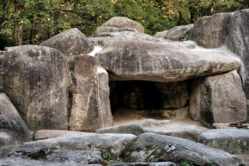 A stone cave made of gigantic rocks a forest.