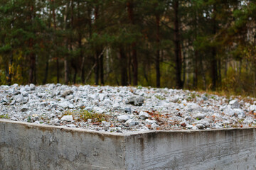 Defocus many crushed stones in mound or memorial. Gravel of jews people. White rock, minerals, archeology, excavations on concrete slab. Outdoor, outside. Pine forest. Close-up. Out of focus