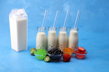 Various Bubble Tea in a glass milk bottles with drink straws on blur background. Take away drinks concept. Mix tapioca pearls for bubble tea. Tapioca boba pearls in bowl.