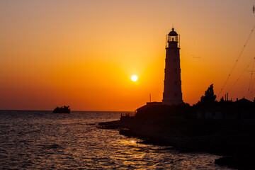 Lighthouse on the sea coast at sunset