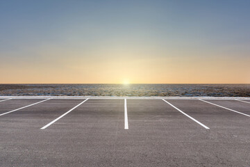Empty parking lot against arid area and beautiful sunset sky. - obrazy, fototapety, plakaty
