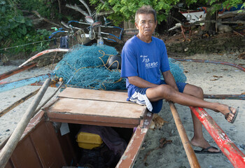 Traditional village fisherman with his banka boat. At home on the beach. Waiting for the tide. Bignayan village, the Philippines