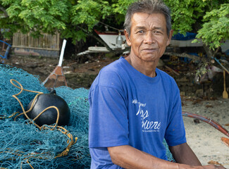 Traditional village fisherman with his banka boat. At home on the beach. Waiting for the tide. Bignayan village, the Philippines