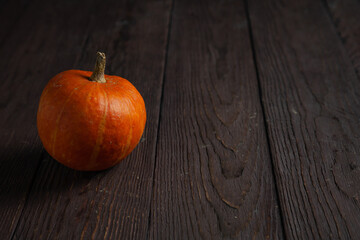 Pumpkin on wooden table in dark mood with copy space.