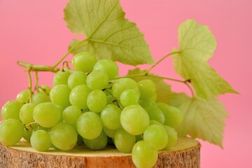 Grape. A bunch of green grapes with leaves on a light pink background.Organic fruits and berries
