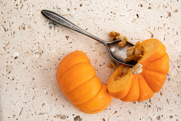 halved small pumpkin with a spoon and seeds, top view, space for copy