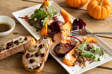 autumn healthy salad with pumpkin or squash, quinoa and greens, shallow depth of field with focus on the center squash slice