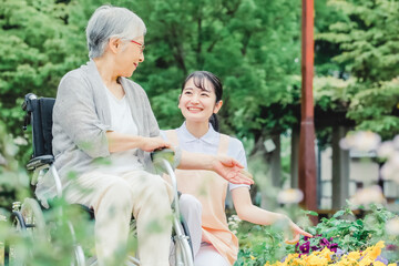 車椅子に乗った高齢者女性と女性スタッフ（花畑）
