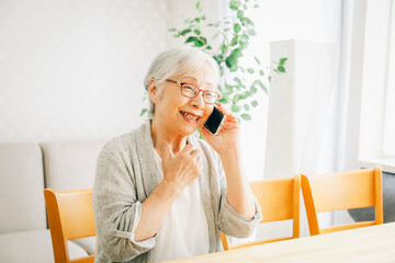 スマホで電話する高齢者女性（笑顔）

