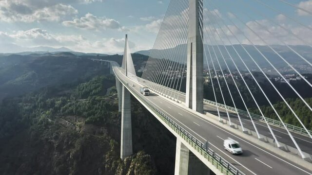 Drone shot of autos moving on Vila Real Bridge crossed Corgo river in mountains, Portugal, Europe. Panoramic view of vehicle building with cars moving on. Green landscape with road bridge, 4k footage