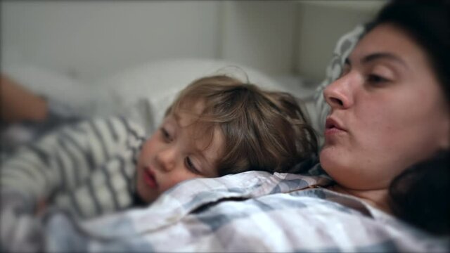 Mom reading bed-time story to toddler son at night before sleep