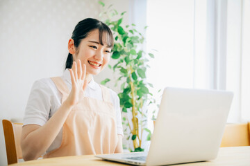 パソコンを使うエプロン姿の女性（笑顔）
