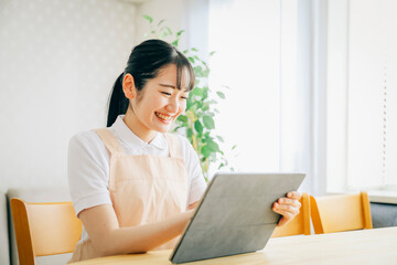 タブレットPCを使うエプロン姿の女性

