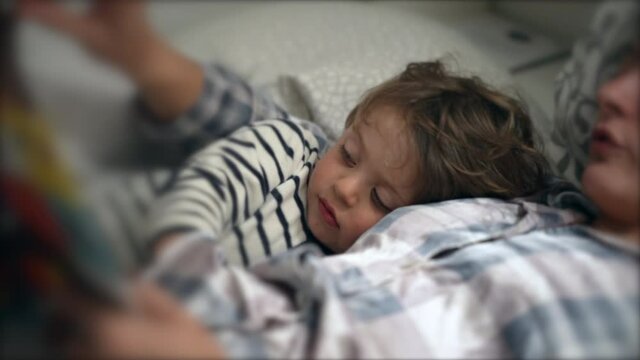 Mother Telling Bedtime Story To Toddler Son Before Sleep