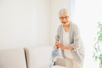 部屋を掃除する高齢者女性（笑顔）
