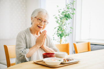 食事をする高齢者女性（合掌）
