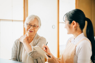 在宅介護を受ける高齢者女性（肩凝り）
