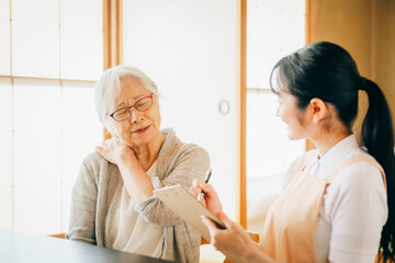 在宅介護を受ける高齢者女性（肩凝り）
